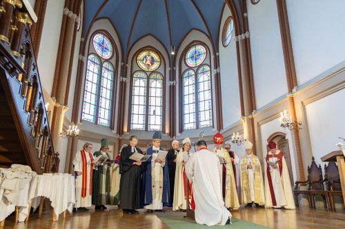 Konsekrācija sākusies; no kreisās: Lielbritānijas Luterāņu baznīcas bīskape emer. Jāna Jēruma–Grīnberga, Somijas Baznīcas bīskape Dr. Mari Parkkinen, Vācijas Ziemeļu baznīcas bīskape Kristina Kühnbaum–Schmidt, Stokholmas bīskaps Andreas Holmberg, Gruzijas luterāņu Baznīcas bīskaps emer. Markus Schoch, LELBP arhchibīskape Lauma Zušēvica, Anglikāņu Baznīcas Eiropas diecēzes bīskaps Robert Innes, Igaunijas Baznīcas bīskaps Marko Tiitus, LELBP archibīskaps emer. Elmārs Ernsts Rozītis; no mugurpuses — bīskaps electus Kārlis Žols